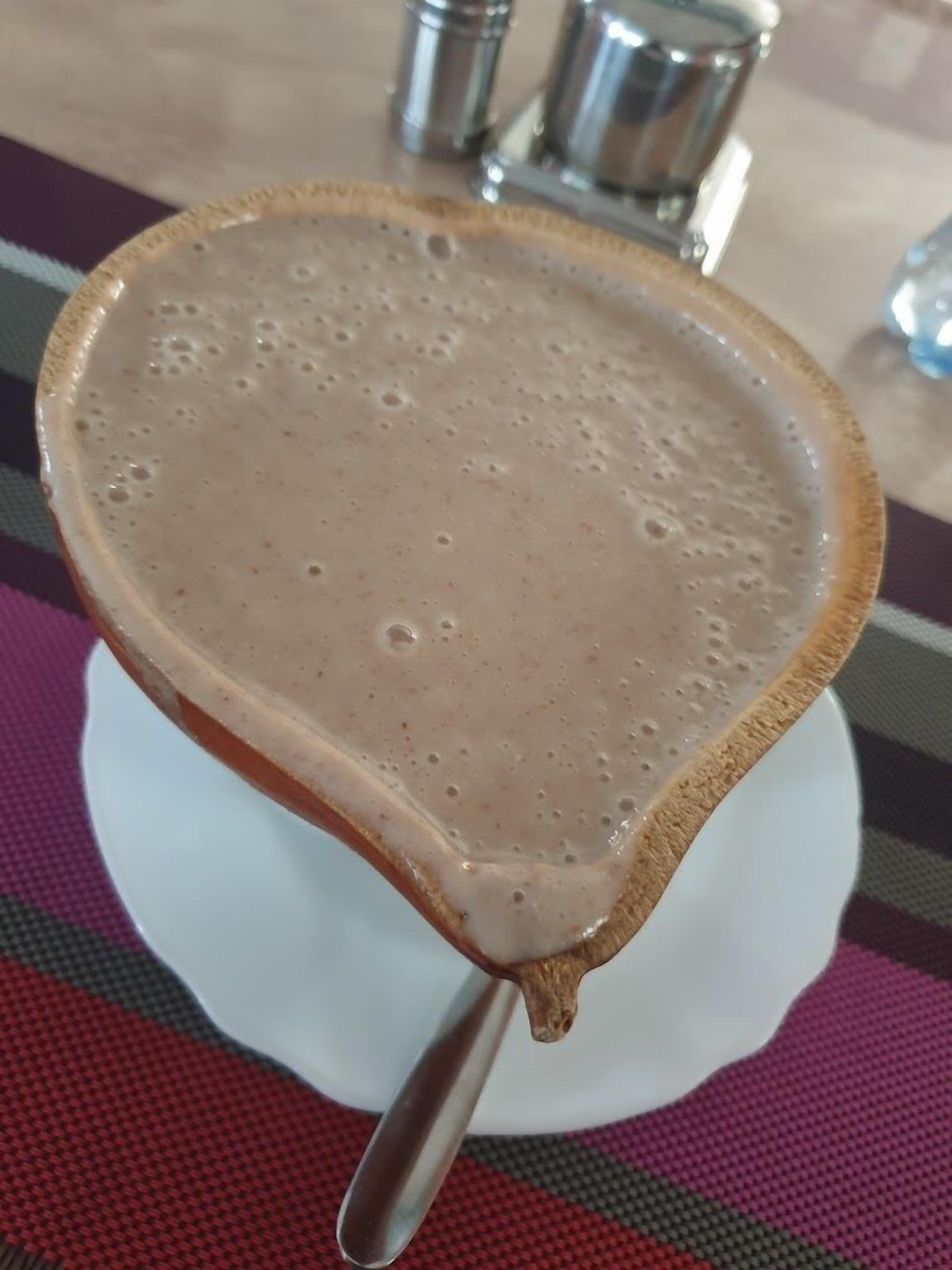 Una bebida en una taza de cerámica con asa, sobre un plato blanco.
