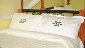 Een bed met witte lakens en twee kussens met tekst erop.
