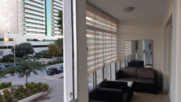 A balcony with a view of a city street, a sofa, and a small table. - Apartamento Beata Para 4 Personas (Calpe)