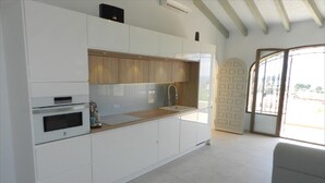 Una cocina moderna con armarios blancos, encimera de madera y horno empotrado.