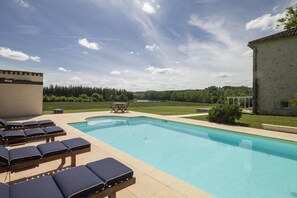 Ein Swimmingpool mit Liegestühlen und Blick auf eine bewaldete Landschaft.