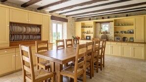 Zona pranzo con tavolo e sedie in legno, circondata da mobili gialli contenenti diversi oggetti da cucina.