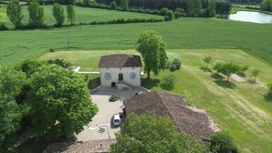 Una casa a due piani con tetto in tegole, un portico e un vialetto con un'auto parcheggiata.