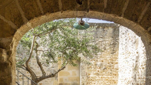 An arched stone corridor with a bench, a chair, and a staircase. - La Petite Baronne - in the Heart of the Gard (Saint-Hilaire-d'Ozilhan)