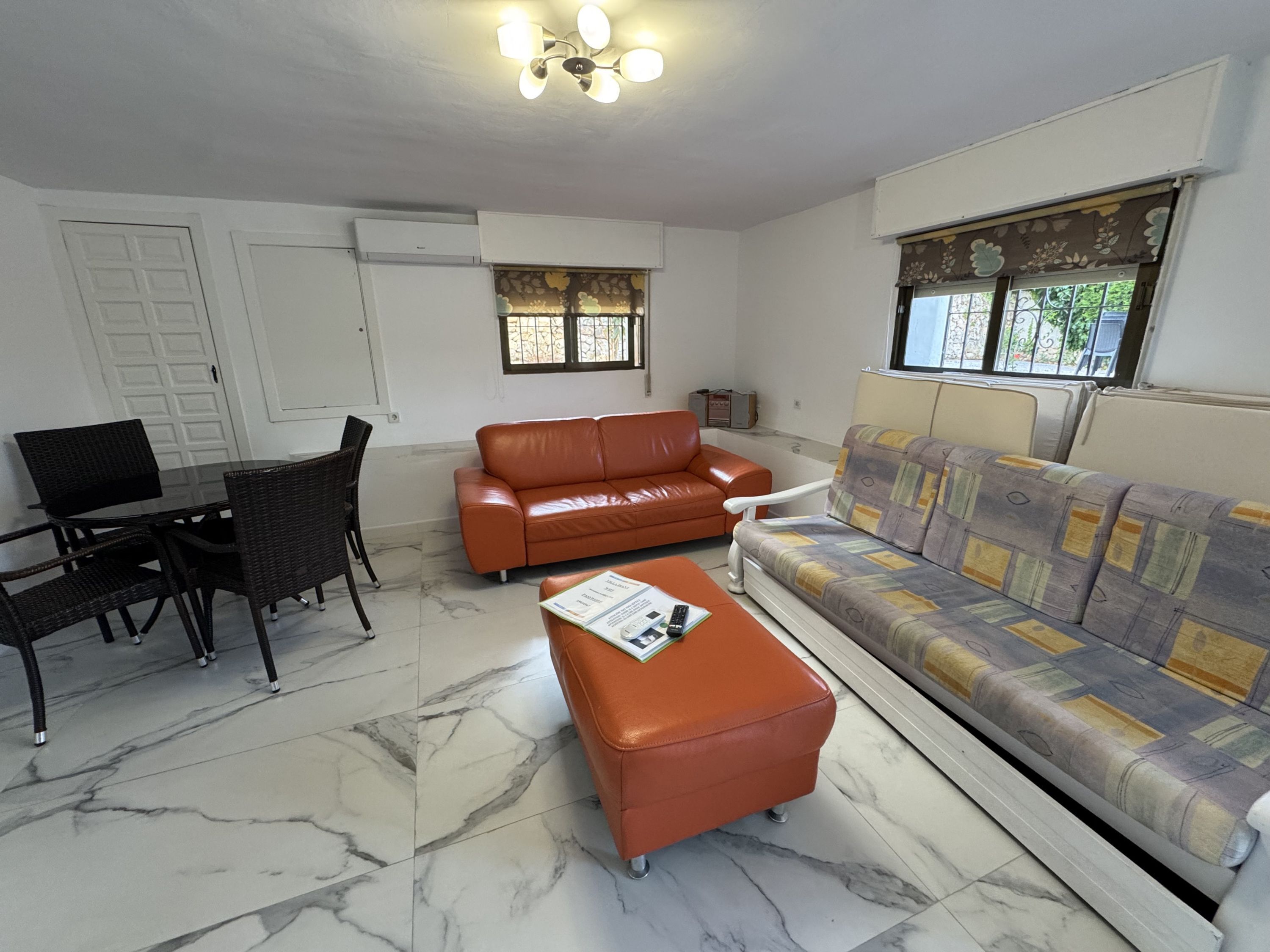 A living room with a sofa, a coffee table, and a dining area with chairs and a table.