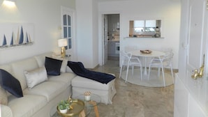 A modern living room with a sofa, coffee table, and a dining area with chairs and a table. - Apartamento Mar Timo 4 Personas (Calpe)