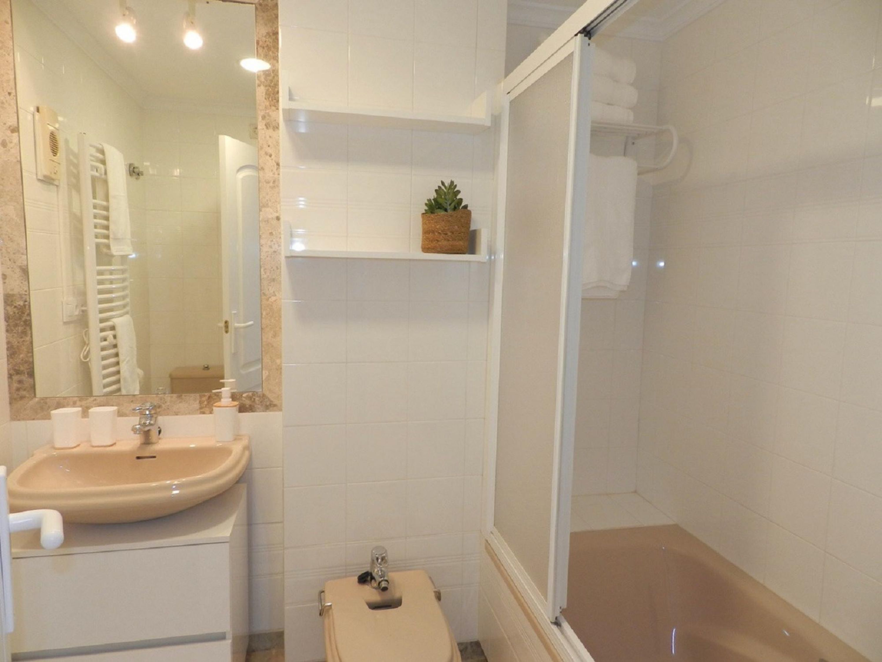 A bathroom with a sink, toilet, and shower area.