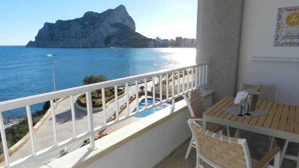 A balcony with a view of the sea and a mountain. There is a table and chairs on the balcony. - Apartamento Mar Timo 4 Personas (Calpe)