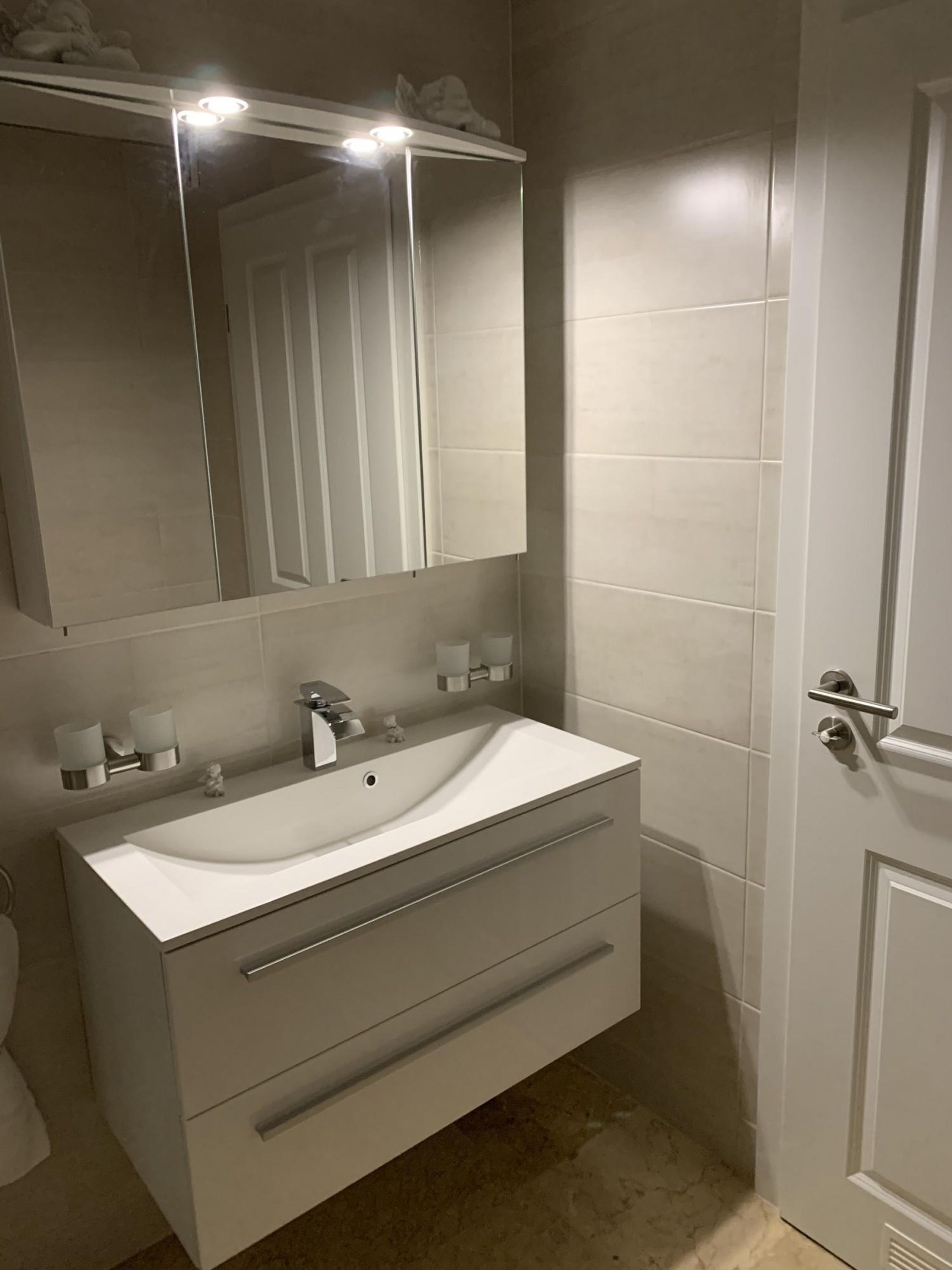 A bathroom with a white sink, a mirror, and a door.