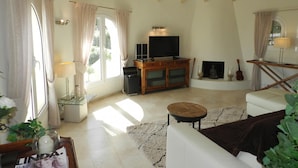A living room with a TV, wooden cabinet, and a fireplace. There is a sofa, a small round table, and a lamp. - Casa Isabel Para 4 Personas (Calpe)