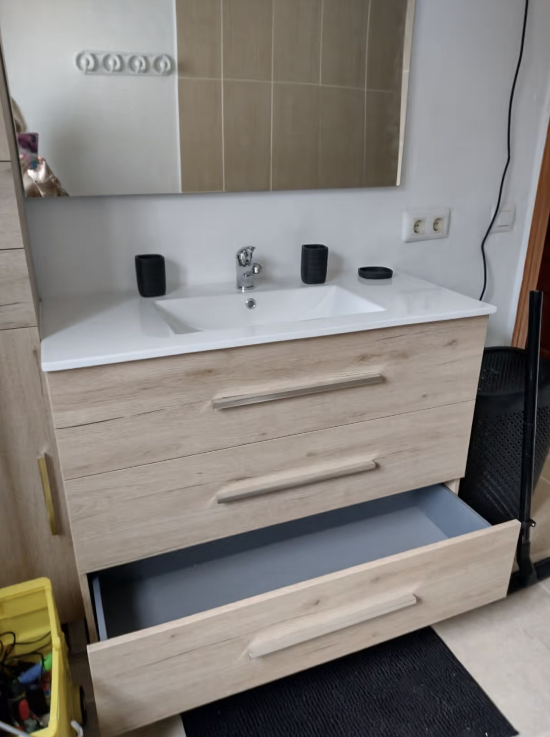A bathroom with a white sink, a mirror above it, and a wooden vanity with drawers.