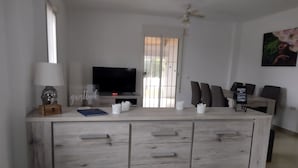 Una cocina moderna con una isla central, televisión y un comedor con sillas.