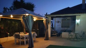 Un patio al aire libre con piscina, mesas y sillas.