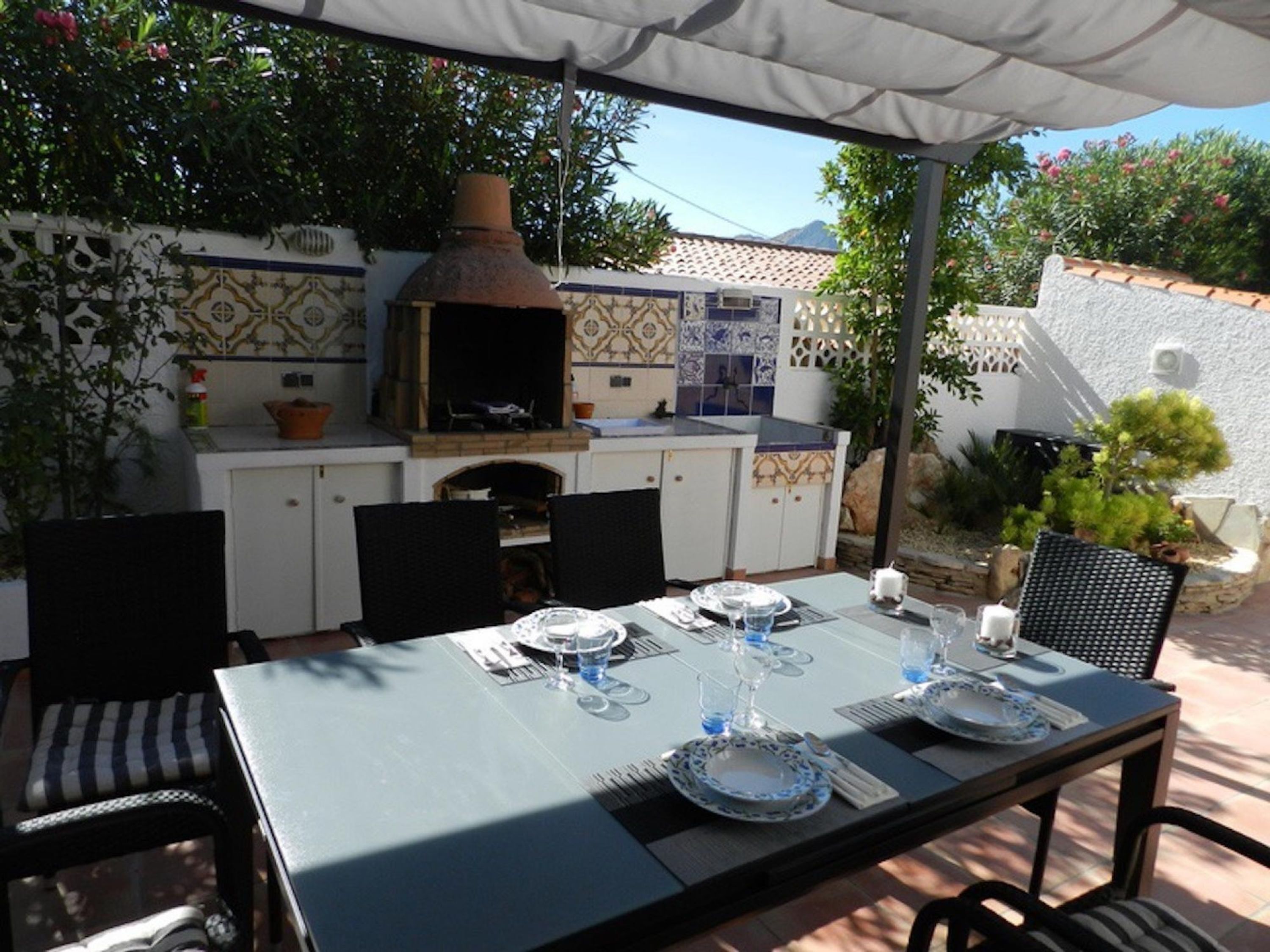 Une terrasse extérieure avec une table à manger pour quatre personnes, entourée de chaises.