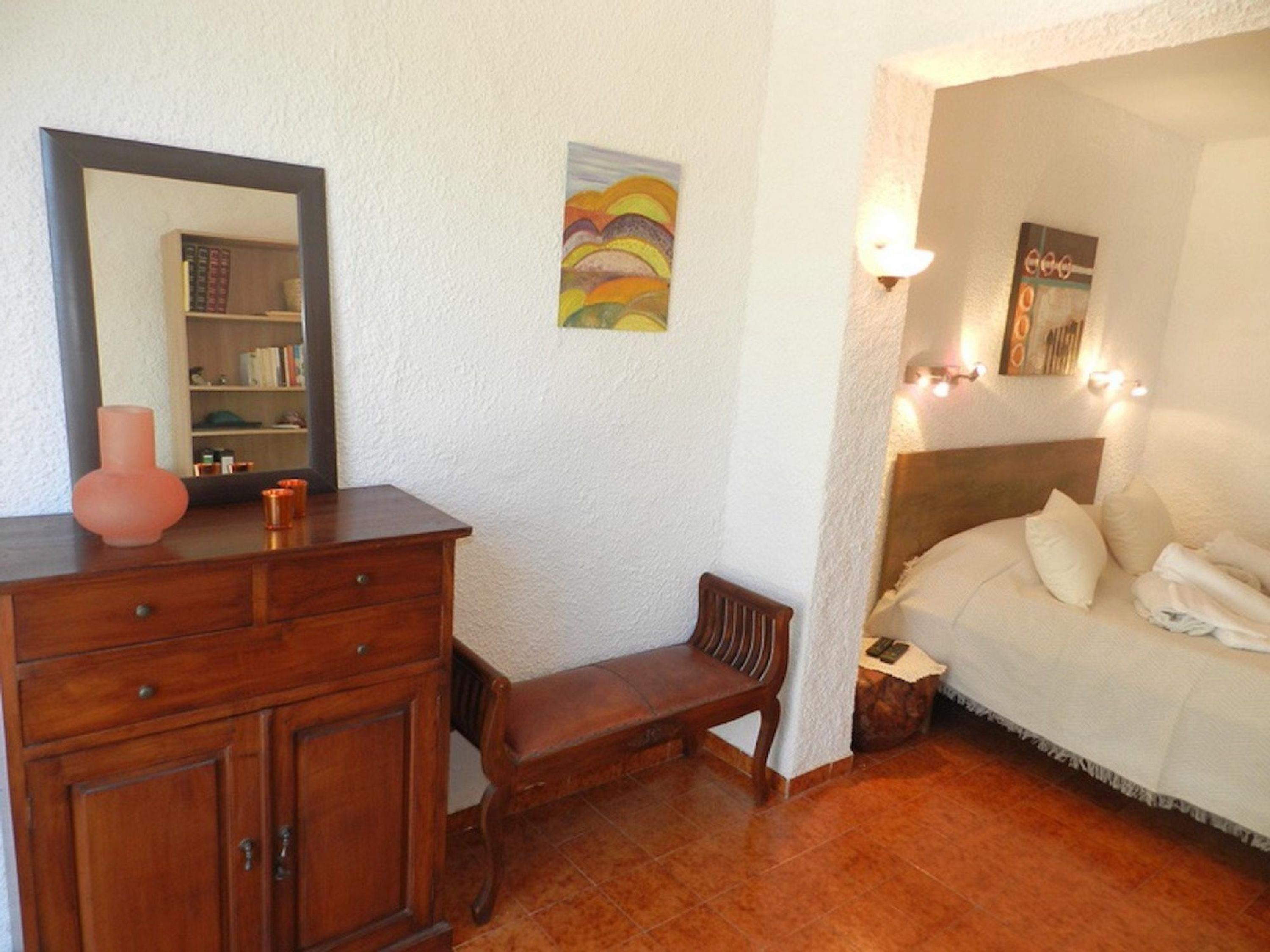 Une chambre à coucher comprenant un lit, une table de chevet, une commode et un miroir.