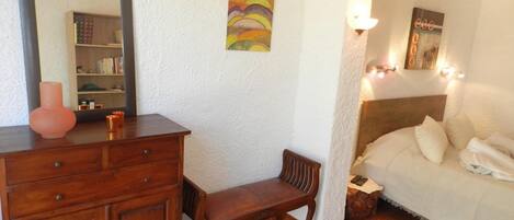 Une chambre à coucher comprenant un lit, une table de chevet, une commode et un miroir.