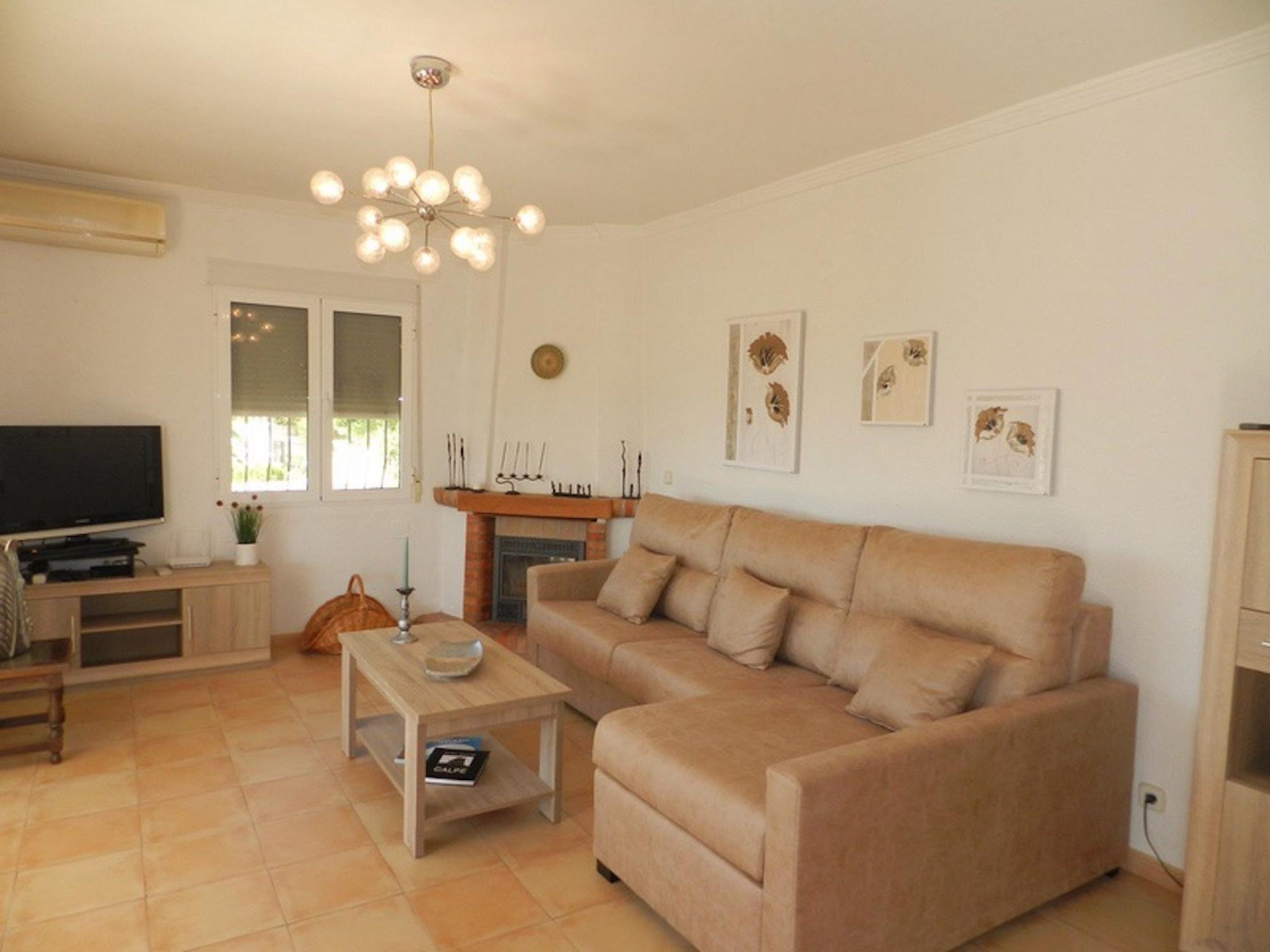 A living room with a beige sofa, a wooden coffee table, a TV, and a fireplace.