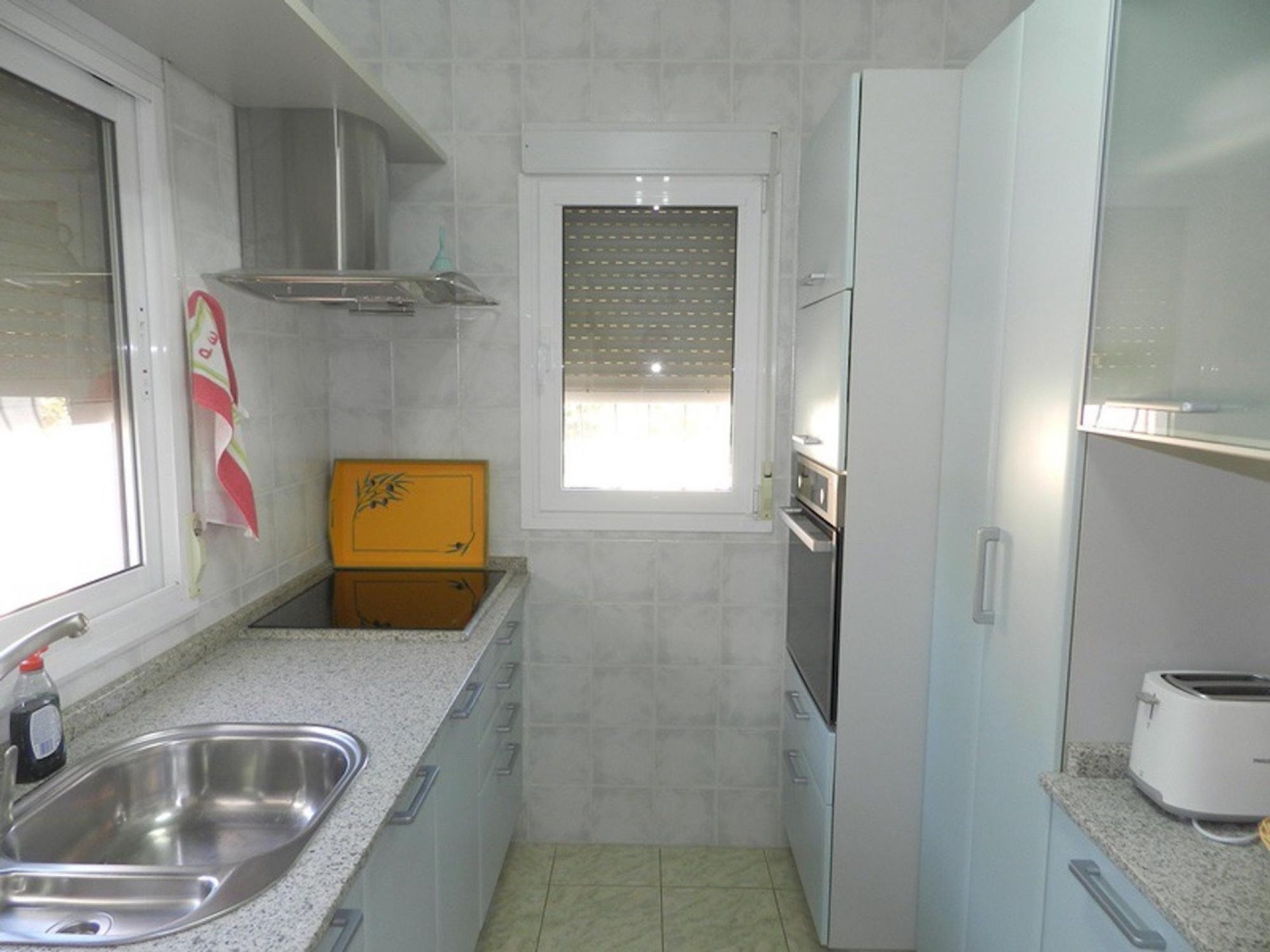 A compact kitchen with a sink, stove, and a window.