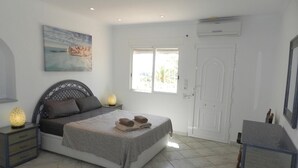 Un dormitorio con cama, lámparas de noche, un cuadro, una ventana y una puerta.