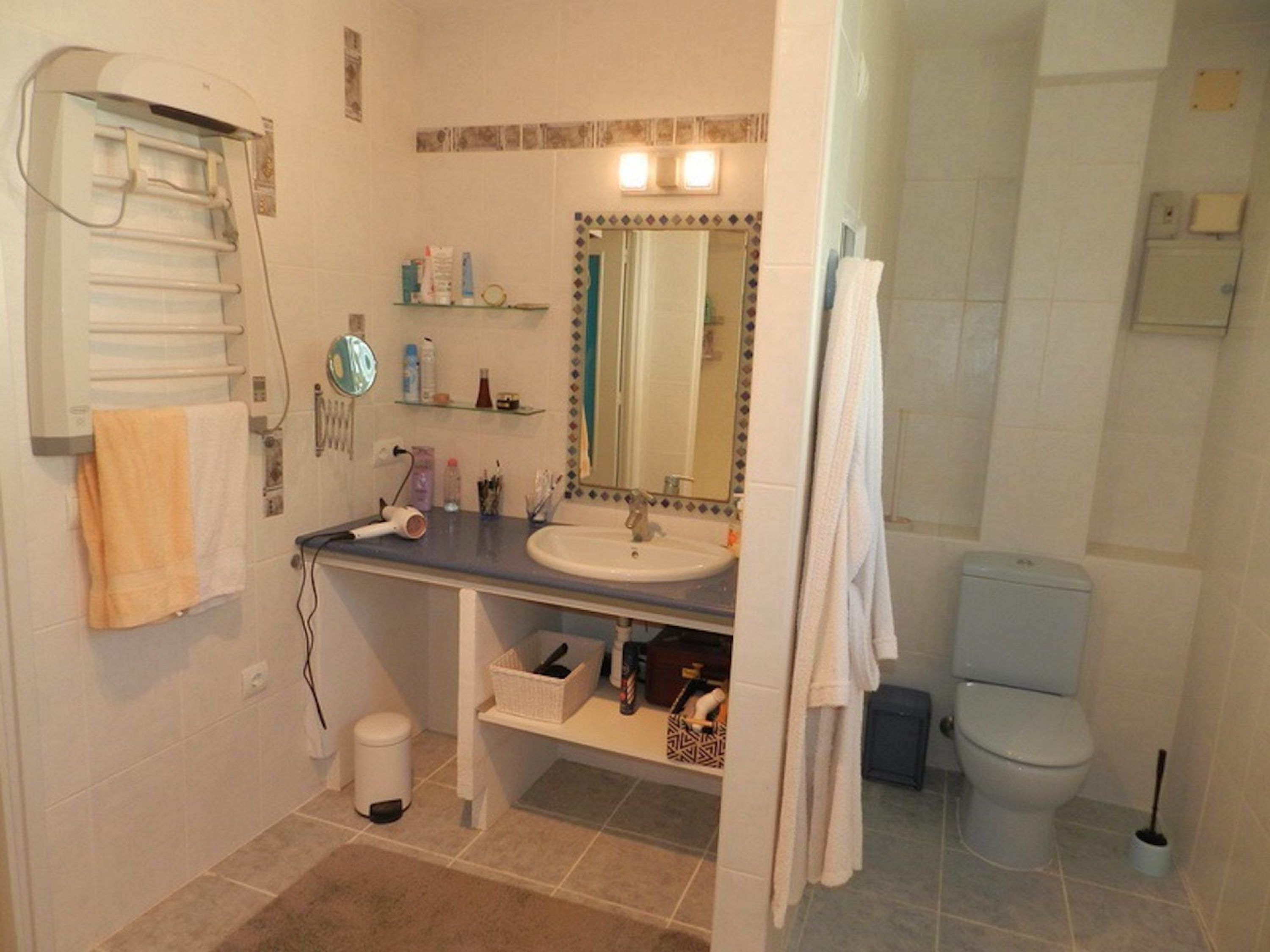 A bathroom with a sink, mirror, towel rack, and toilet.