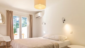 Une chambre à coucher avec un lit, une chaise, une table et une vue sur l’extérieur.