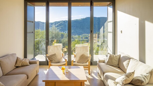 A modern living room with a sofa, two armchairs, and a coffee table. Large windows offer a view of a mountainous landscape. - La Maison des Chataigniers (Meyrannes)