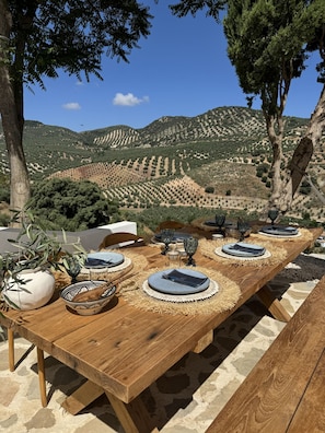 Una mesa de comedor de madera al aire libre, con vistas a un viñedo pintoresco.