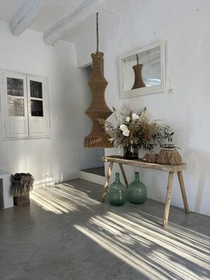 A room with a wooden table, green bottles, a hanging crochet light, a mirror, and a white door with glass panels. - Vista Las Colinas in Izn jar (Iznajar)