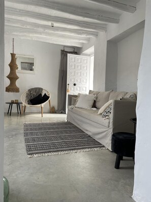 A living room with a sofa, a hanging chair, a patterned rug, and a white door. - Vista Las Colinas in Izn jar (Iznajar)