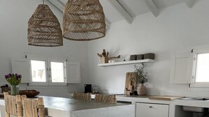 A modern kitchen with a central island, wicker chairs, and pendant lighting. - Vista Las Colinas in Izn jar (Iznajar)