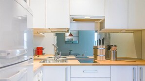 A modern kitchen with white cabinets, a stainless steel sink, and a wooden countertop. - Colon 902 in Madrid With 1 Bedrooms and 1 Bathrooms (Madrid)