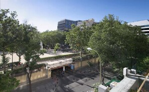 A street view with a pedestrian crossing, trees, and modern buildings in the background.