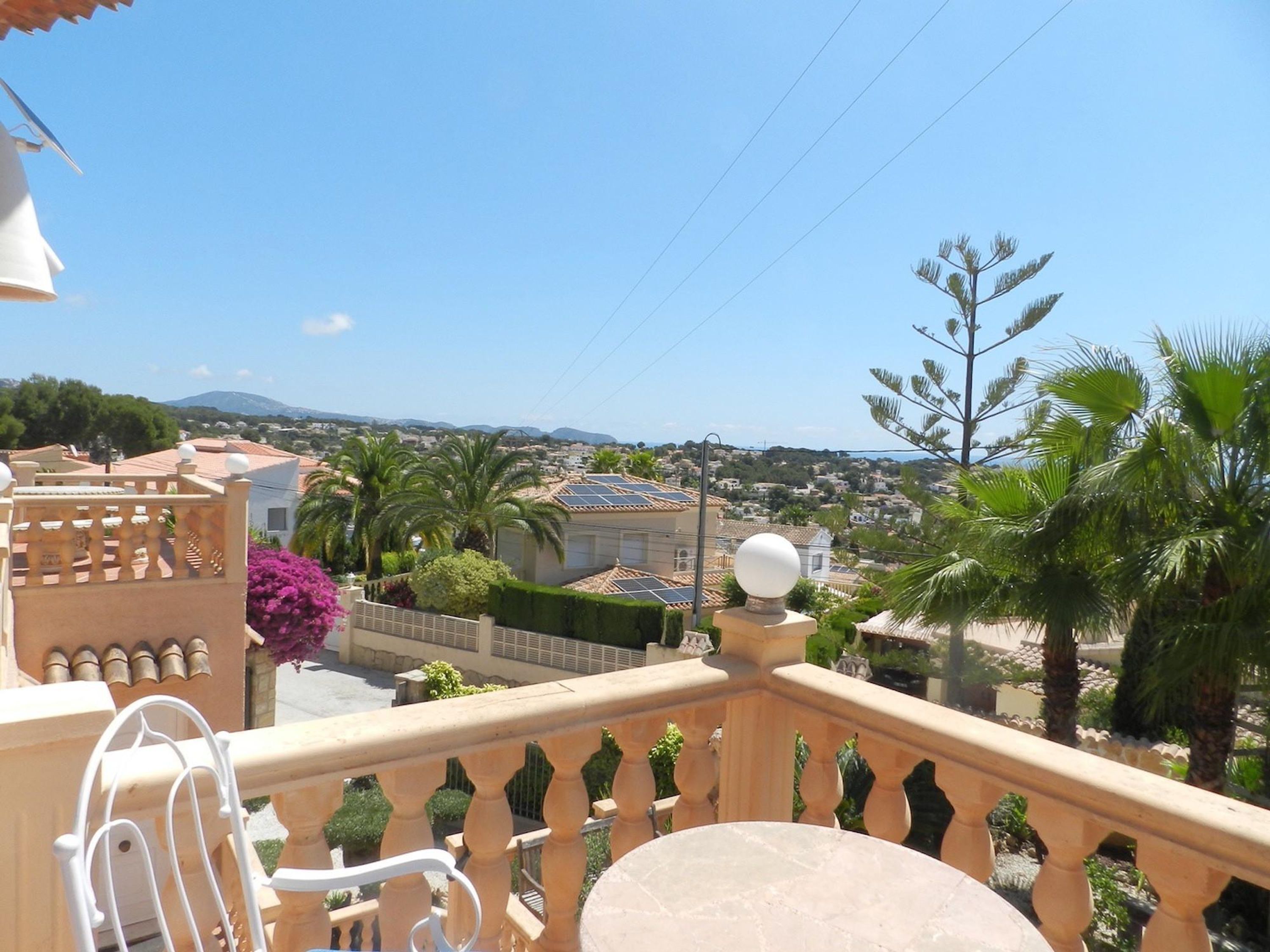 A balcony with a view of a residential area, including houses and palm trees.