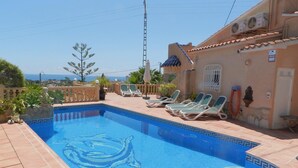 A swimming pool with a dolphin design, surrounded by lounge chairs and a view of the sea. - Villa Ambiente Para 4 Personas (Calpe)