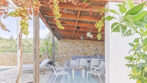 An outdoor patio with stone walls, white furniture, and hanging plants. - Casa Olivo in Izn jar (Iznajar)
