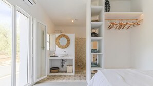 A modern bedroom with a large bed, a built-in wardrobe, a vanity with a mirror, and a shower area. - Casa Olivo in Izn jar (Iznajar)