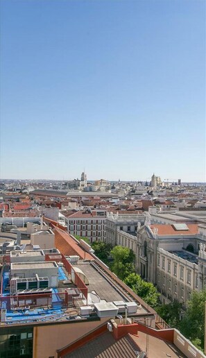 A rooftop with a swimming pool, surrounded by urban buildings and clear skies.