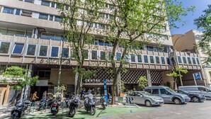 Ein mehrstöckiges Gebäude mit Parkplatz und mehreren parkenden Motorrädern davor.