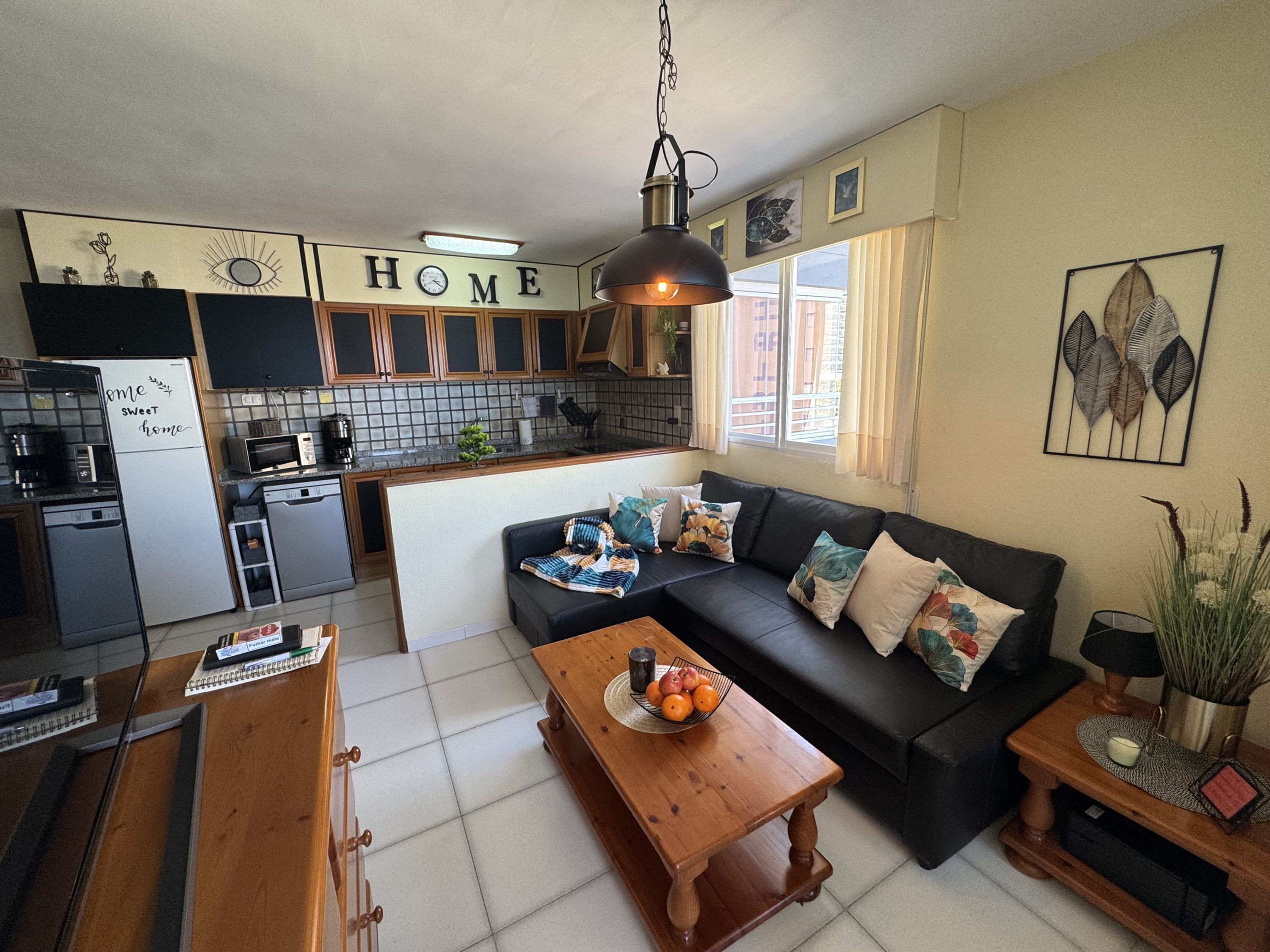 Un espacio habitable compacto con kitchenette, un sofá, una mesa de centro y una mesa de comedor.