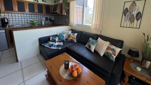 A modern kitchen with wooden cabinets, a black sofa with patterned cushions, and a wooden coffee table with fruit. - Apartamento Luise Para 4 Personas (Calpe)