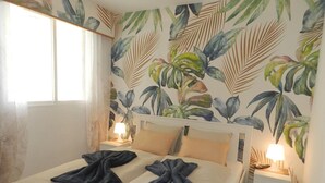 A double bed with beige linens, two dark towels, and a nightstand with a lamp. - Apartamento Luise Para 4 Personas (Calpe)