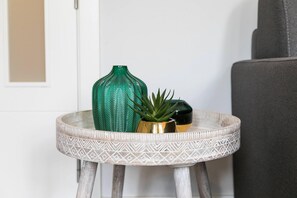 A small round table with a geometric pattern, a green vase, a gold pot, and a green plant. - Mm26 I 4C in Madrid With 2 Bedrooms and 2 Bathrooms (Madrid)