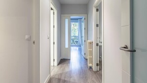 Ein Flur mit weißen Wänden und Holzboden, der zu einem Balkon mit Tisch und Stühlen führt.