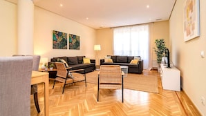 A modern living room with a herringbone floor, two dark sofas, a wicker chair, a small table, and a white side table. - Ddl20 I 2A in Madrid (Madrid)