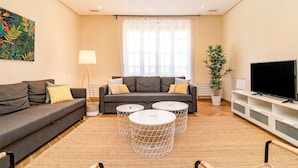 A modern living room with a grey sofa, two round coffee tables, a TV, and a large window with sheer curtains. - Ddl20 I 2A in Madrid (Madrid)