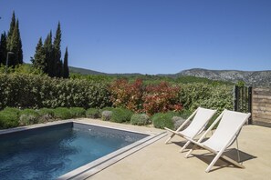 A swimming pool with two lounge chairs, surrounded by greenery and a mountainous backdrop. - Villa Tica in Malauc ne (Malaucene)