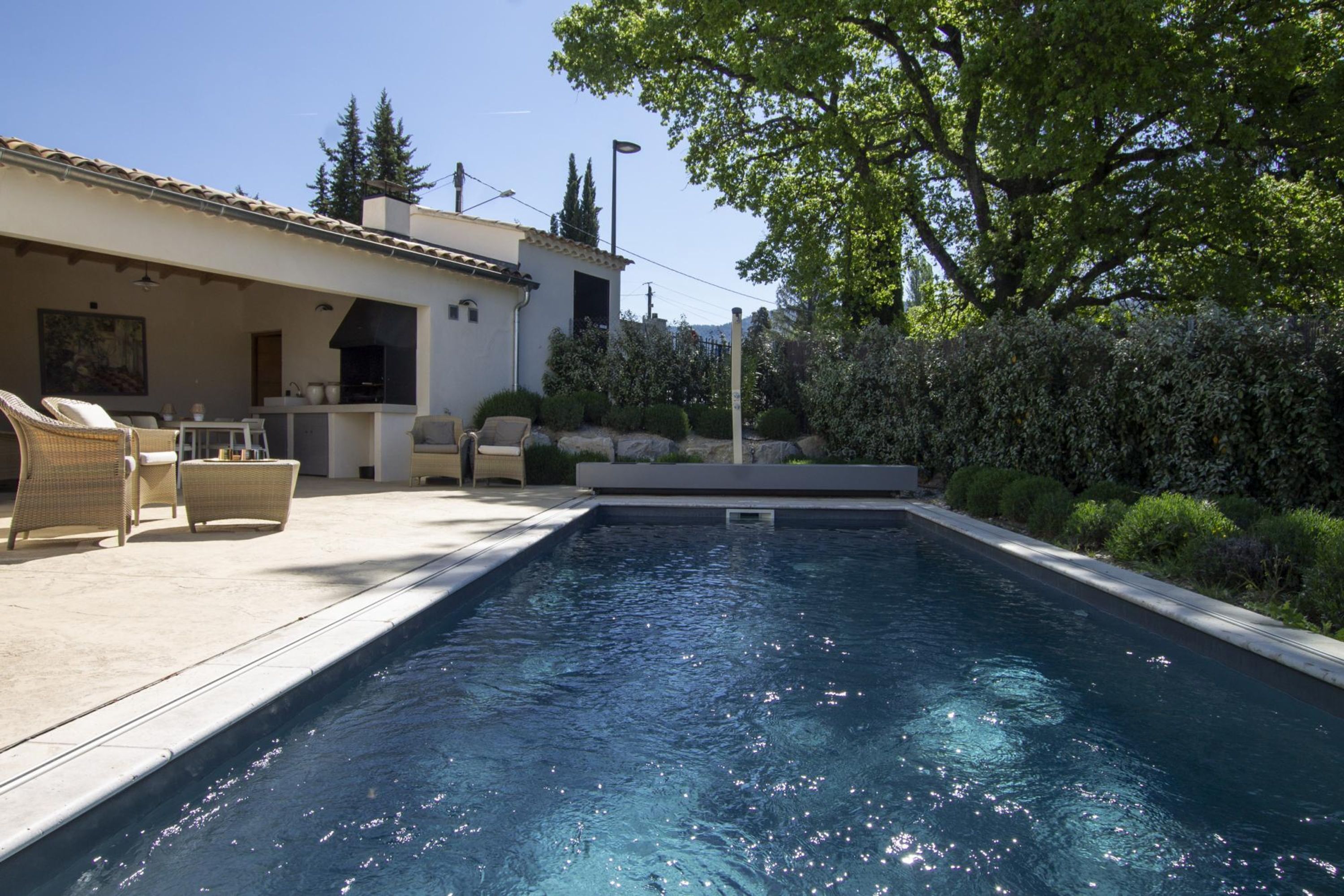 A swimming pool with lounge chairs and a barbecue area.