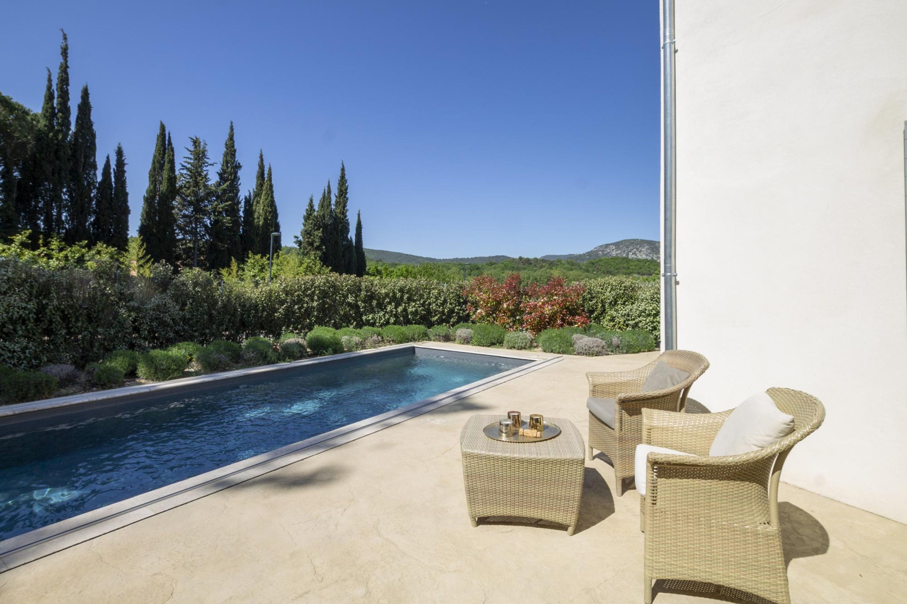 A poolside area with wicker furniture and a view of a mountainous landscape.