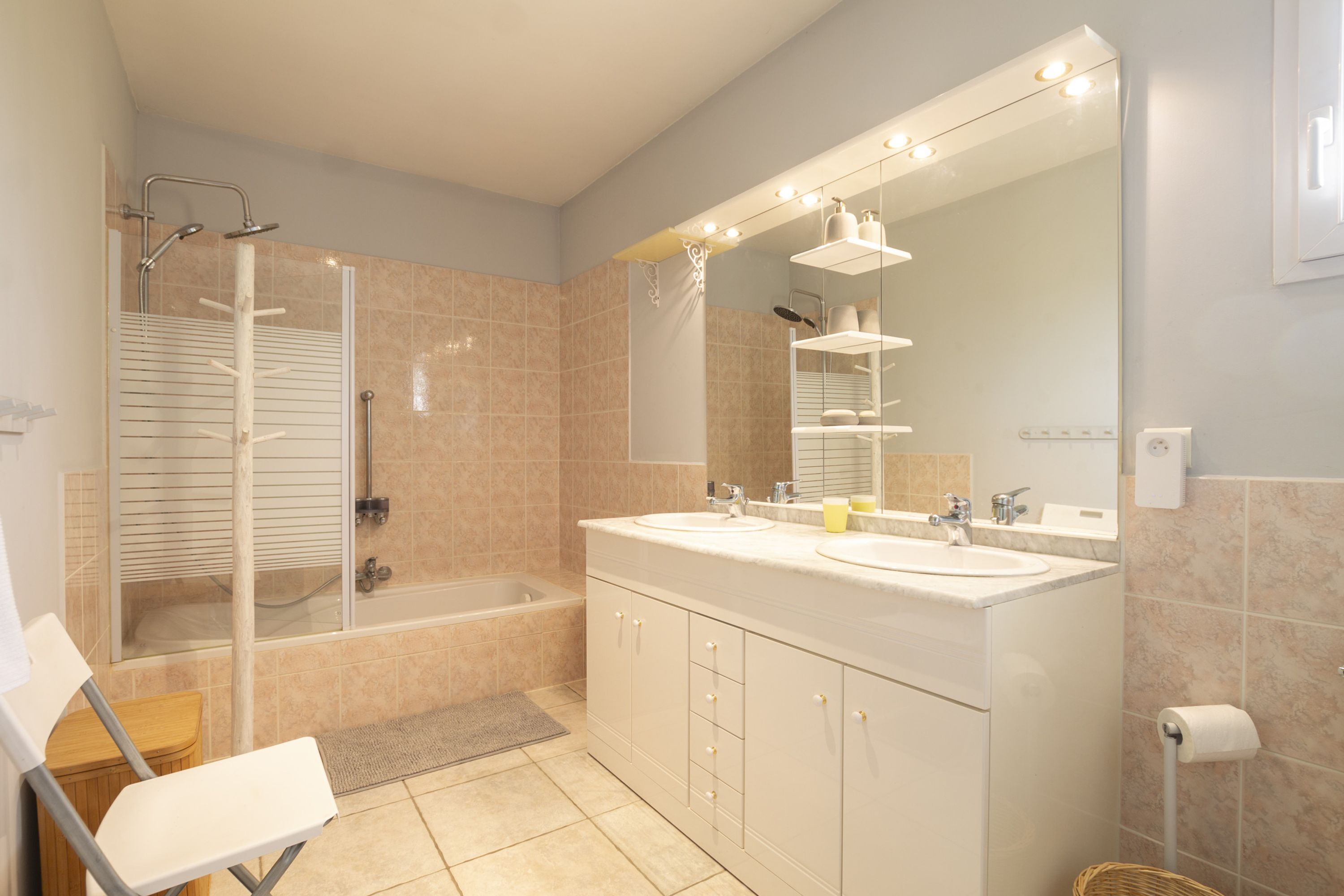 A modern bathroom with a shower, bathtub, and dual sinks.