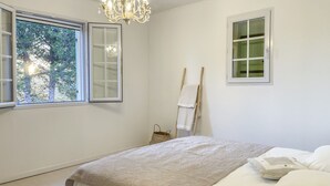 Une chambre à coucher avec un lit, une fenêtre, un lustre et un tableau au mur.